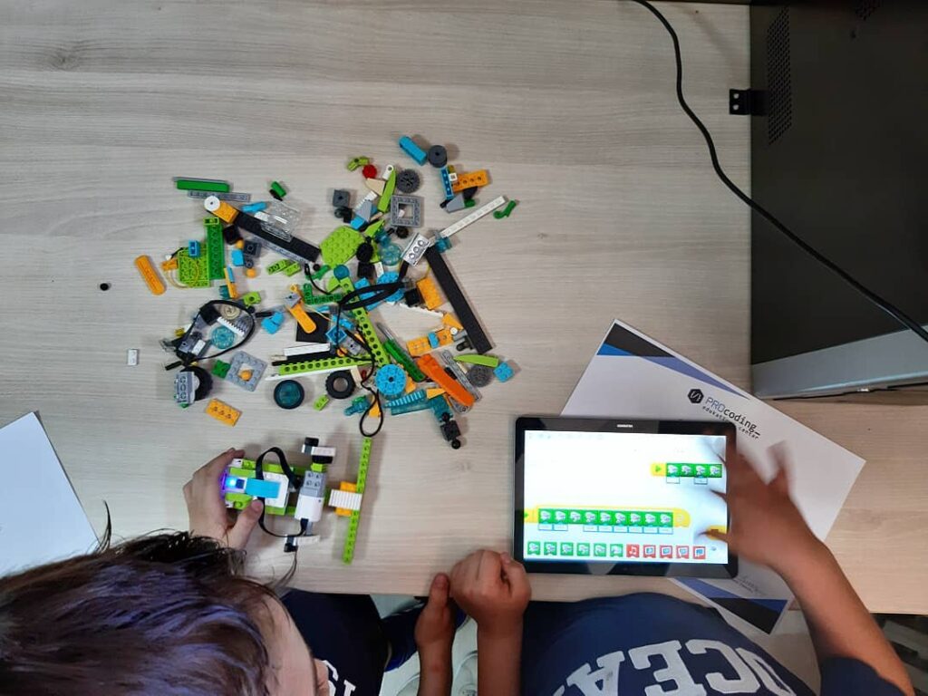 Delovi LEGO kompleta na stolu, dete sklapa robota uz tablet