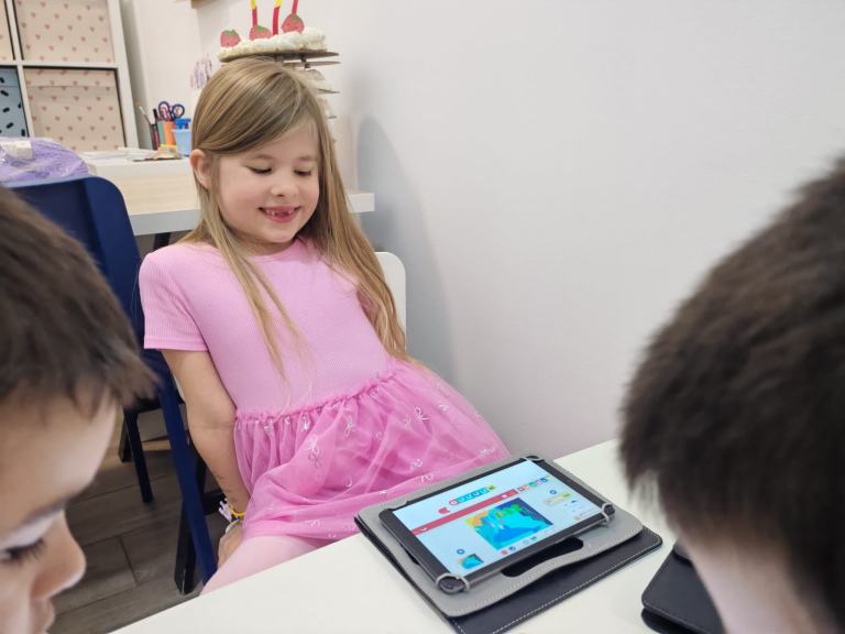 Devojčica radi na tabletu na času, oko nje ostala deca
